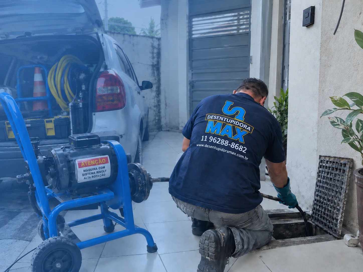Profissional de desentupimento realizando serviço com equipamento especializado